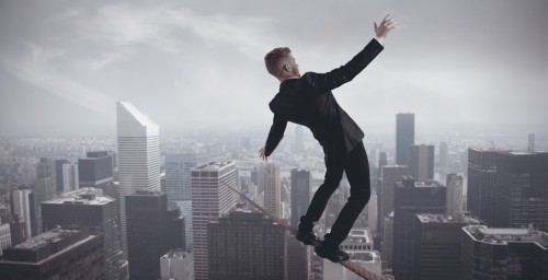 Мужчина балансирует на канате натянутом с крыши одного здания на другое