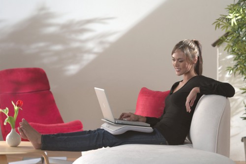 Девушка сидит на диване и в руках держит ноутбук