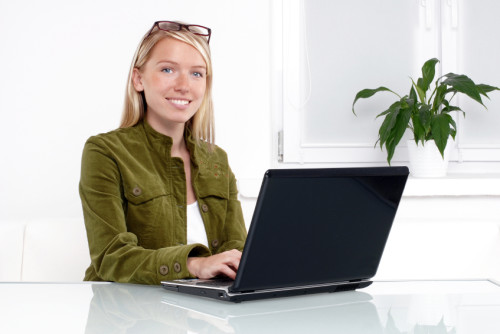 Симпатичная девушка сидит за ноутбуком