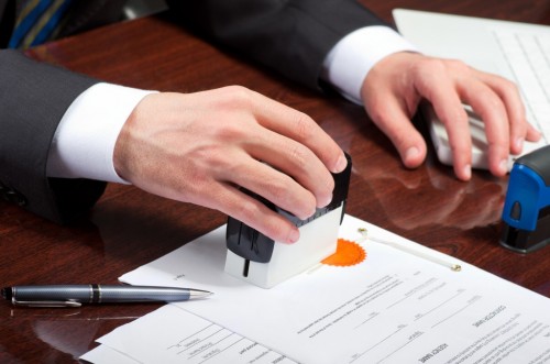Мужчина ставит печать на документ
