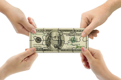 Руки людей держат 100 долларовую купюру