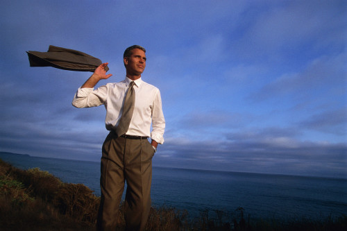 Мужчина Альфа Самец стоит на скале на берегу моря