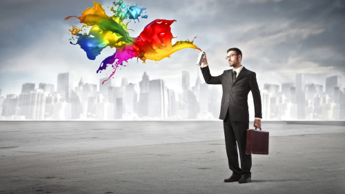 Мужчина в деловом костюме разбрызгивает из баллончика краску