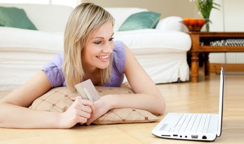 Девушка лежит на полу напротив ноутбука