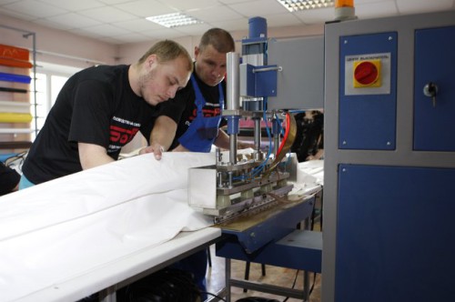 Работники сваривают края натяжного потолка