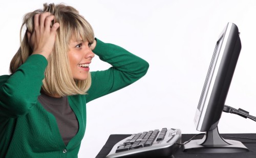 Блондинка смотрит удивлённо на монитор компьютера